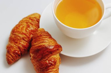 Beyaz arka planda bir fincan çayla birlikte kruvasanlar. Bir fincan sade kahveyle kahvaltı, beyaz tabakta kruvasan, beyaz arka planda izole edilmiş..