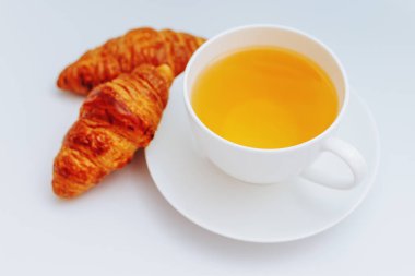 Beyaz arka planda bir fincan çayla birlikte kruvasanlar. Bir fincan sade kahveyle kahvaltı, beyaz tabakta kruvasan, beyaz arka planda izole edilmiş..