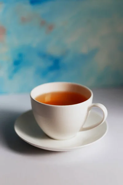 青の背景にお茶とソーサーの白いカップ 青のグランジの背景に白いテーブルの上の青いコーヒーカップ — ストック写真