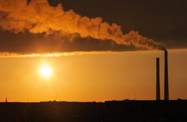 Gün batımı sırasında şehir evlerin çatıları. Koyu duman termik santral kanaldan geliyor.