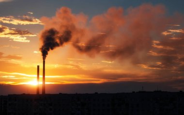 Renkli Sihirli Günbatımı. Gün doğumunda şehir evlerinin çatıları. Kuşlar gökyüzünde uçuyor. Termik santral borusundan siyah duman geliyor..