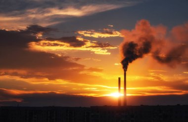 Renkli Sihirli Günbatımı. Gün doğumunda şehir evlerinin çatıları. Kuşlar gökyüzünde uçuyor. Termik santral borusundan siyah duman geliyor..