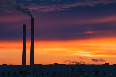 Renkli Sihirli Günbatımı. Gün doğumunda şehir evlerinin çatıları. Termik santral borusundan siyah duman geliyor..