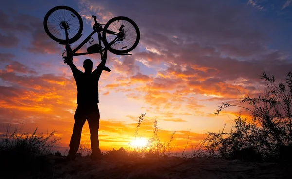 Silhueta Homem Ficar Ação Levantando Bicicleta Acima Sua Cabeça Prado — Fotografia de Stock