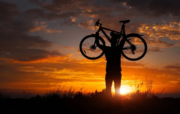 Silhueta Homem Ficar Ação Levantando Bicicleta Acima Sua Cabeça Prado — Fotografia de Stock