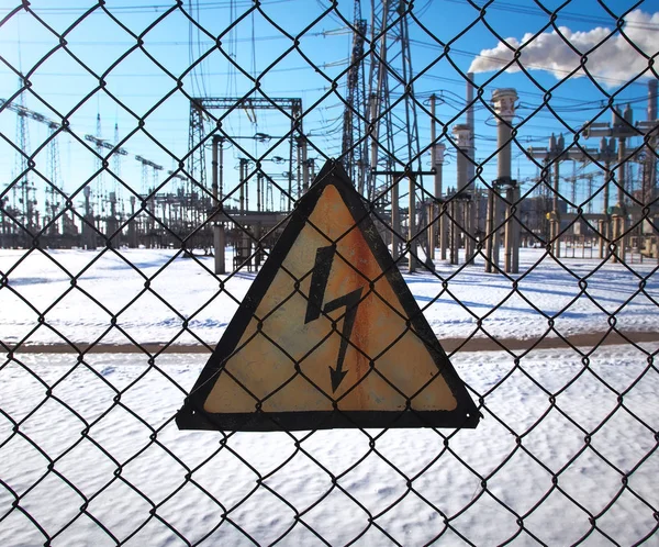 High-voltage transformer substation behind barbed-wire chain-link fence with Danger High Voltage sign