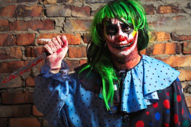 Çılgın palyaço bir tuğla duvar arka planda bir bıçakla. Cadılar Bayramı kavramı