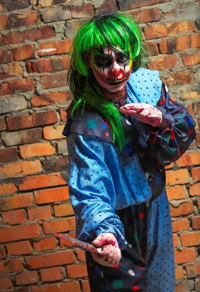 Çılgın palyaço bir tuğla duvar arka planda bir bıçakla. Cadılar Bayramı kavramı