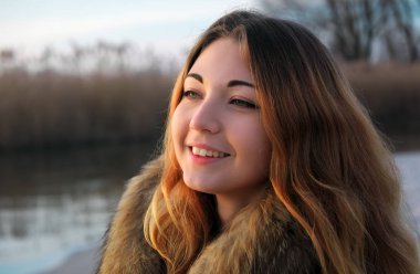 Açık havada yakınındaki sunris donmuş gölde kış kırmızı yanakları güzel genç gülümseyen kız portresi