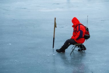 Genç bir adam bir delikten buzda balık tutuyor. Balık tutma kış. 