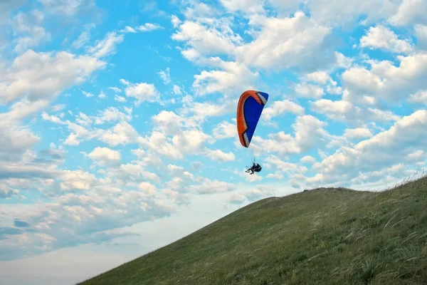 Trike with a parachute against the blue sky. Paragliding flying over the clouds