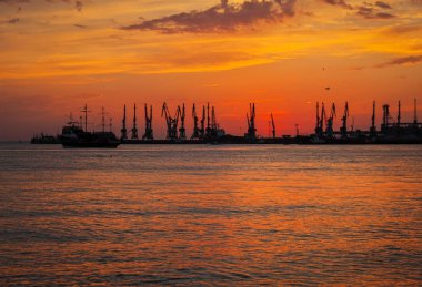 Ateşli gün batımı gökyüzü ve deniz ile güzel manzara. Liman üzerinde