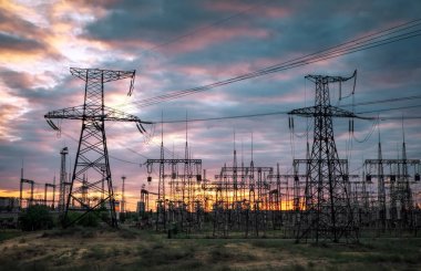 Gün batımında elektrik hatları ve trafolar olan elektrik santrali.