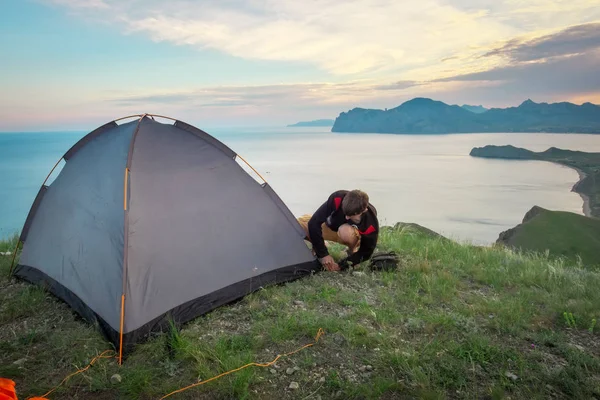 Tourist sets up a tent on the top of a mountain overlooking the