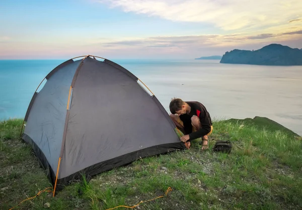 Tourist sets up a tent on the top of a mountain overlooking the