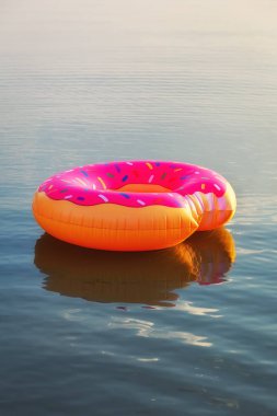 Gün doğumu saatinde suda büyük şişme çörek. Hipster serpilir