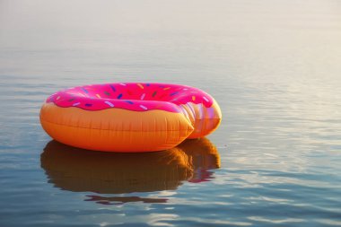 Gün doğumu saatinde suda büyük şişme çörek. Hipster serpilir