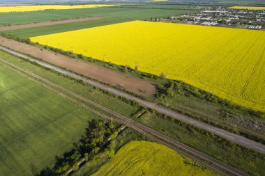 Sarı ve yeşil tecavüz alanları, hava manzaralı. Arabalar yola koyulur..