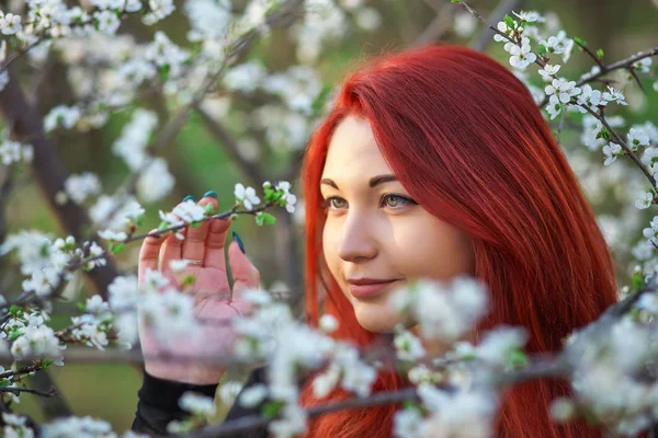 La chica con el pelo rojo inhala la fragancia de las flores de t —  Fotos de Stock
