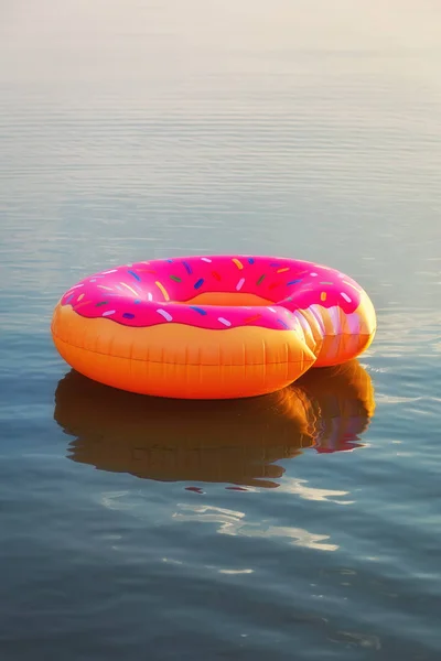Μεγάλο φουσκωτό ντόνατ στο νερό την ώρα της αυγής. Χίππις με ψεκάζονται — Φωτογραφία Αρχείου