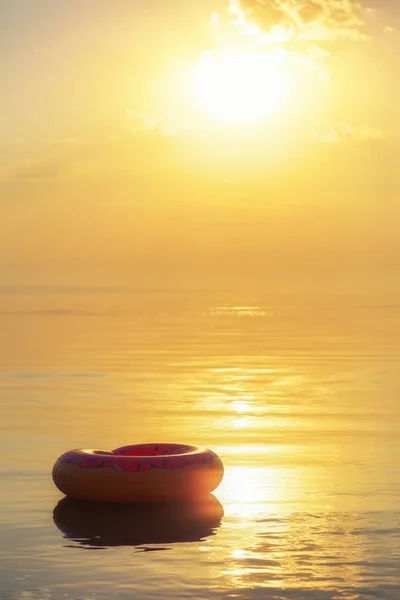 日の出時間に水に大きな膨脹可能なドーナツ。ヒップスター振りかける — ストック写真