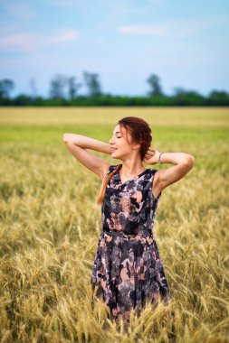 Gün batımında buğday tarlasında sevimli çekici genç kız. Dalgın