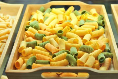 Dükkan wi ahşap tepsi üzerinde pişmemiş renkli makarna closeup