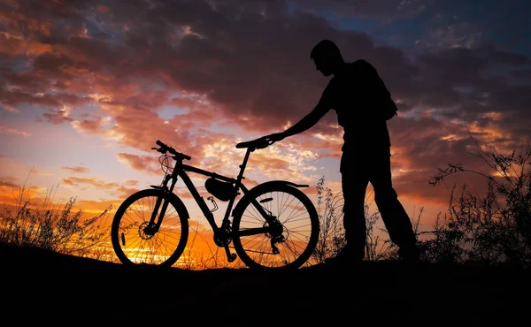 Sylwetka osoby sportowej na rowerze na łące na pięk — Zdjęcie stockowe
