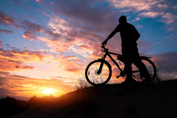 Silhouette of sports person cycling on the meadow on the beautif — Stock Photo, Image