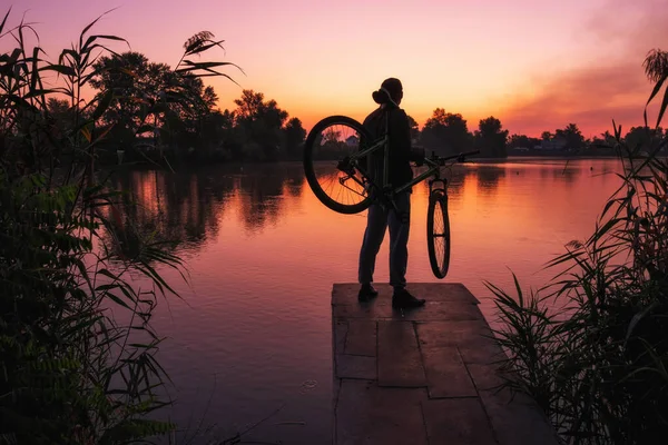 Homem com uma bicicleta no mirante admira o nascer do sol ou pôr do sol . — Fotografia de Stock