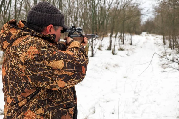 Jäger mit Scharfschützengewehr im Winterwald. Ein Mann schaut zu — Stockfoto