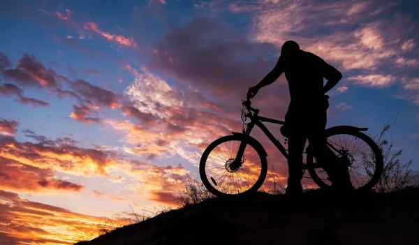 Силуэт спортивного человека, катающегося на велосипеде по лугу на прекрасном — стоковое фото
