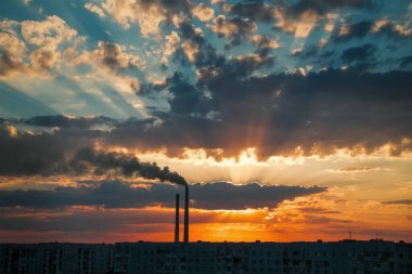 Renkli Sihirli Günbatımı. Gün doğumunda şehir evlerinin çatıları. Termik santral borusundan siyah duman geliyor..