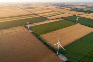 Yenilenebilir yel değirmenlerinin hava görüntüsü, ekolojik enerji sağlayan türbinler. Denizin yanındaki geniş tarım çayırlarında esen rüzgardan enerji alıyorlar. Alternatif elektrik
