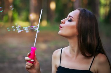 Yaz parkında sabun köpüğü üfleyen mutlu bir kız.