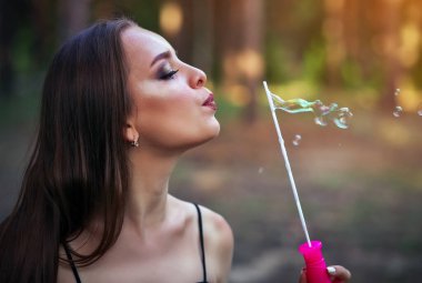 Yaz parkında sabun köpüğü üfleyen mutlu bir kız.