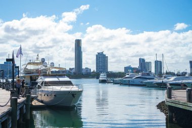Gold Coast, Avustralya - Aralık, 2018: Marina Mirage limanının ve güneşli bir günde yakındaki iskelede demirlemiş beyaz lüks yatların güzel manzarası. 