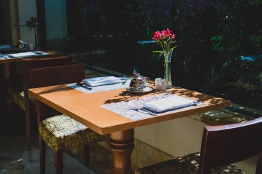 Vazoda çiçeklerle şık ahşap yemek masası, öğle yemeği için hazırlanan.