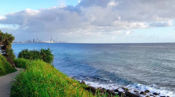 Burleigh Heads Park, Queensland, Avustralya'daki yürüyüş parkurundan görülebilen Gold Coast silüeti nin ve sörf plajının çarpıcı panoramik manzarası.