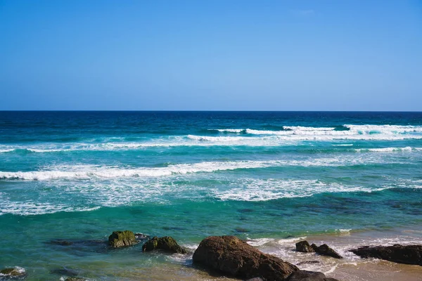 Stunning wide panorama of the Rainbow Bay Beach with surfing ocean waves and Gold Coast skyline on the background, Queensland, Australia.