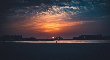 Dubai, Birleşik Arap Emirlikleri 'ndeki Black Palace Plajı' nda gün batımını izleyen bir çiftin silüeti..