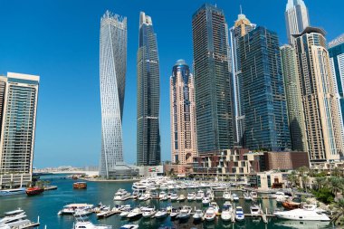Dubai Marina gökdelenlerinin, yatların ve teknelerin göz kamaştırıcı panoramik manzarası güneşli bir günde Dubai Marina rıhtımında demirlemiş. Dubai, Birleşik Arap Emirlikleri.
