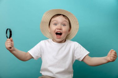 Elinde büyüteç olan bir çocuk. Oyun dedektifi, dedektif, böcek bilimci, biyolog, renkli mavi bir arka planda izole edilmiş..