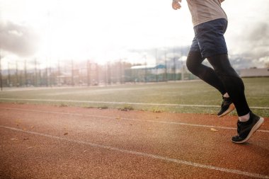 Spor sahası. Gün batımında koşu bandında çalışan bacaklar. Sağlıklı yaşam tarzı kavramı