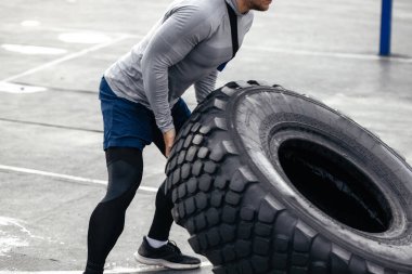 Kafkas görünümlü erkek sporcu, direksiyonu kaldırıyor. Açık hava spor sahasında güç antrenmanı. Ağır egzersizler yapıyor. En sevdiğim çalışma. yumuşak odak