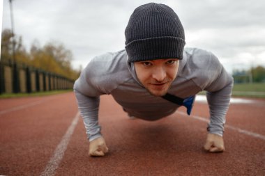 Alt manzara, yetişkin beyaz bir erkek tarafından yapılmış. Stadyum eğitiminde bir atlet yaz günü, sağlıklı bir yaşam biçimi olan gerçek bir insan konsepti sunar. Yakın çekim.