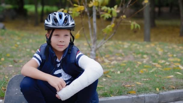 Caucasian boy sitting on the border with his skate — Stock Video