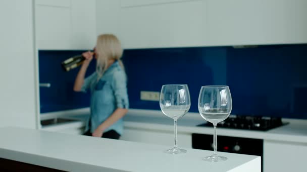 忧郁的白种女人在厨房的瓶子里喝葡萄酒 — 图库视频影像