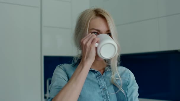 Jonge wit vrouw drinken koffie op de moderne keuken — Stockvideo