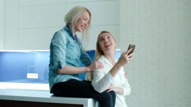 İki kadın fotoğrafları Smartphone izlerken